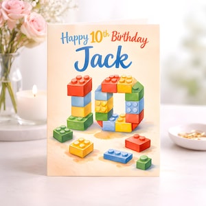 May include: A birthday card with the text "Happy 10th Birthday Jack" in red and blue. The card features a colorful illustration of the number 10 made of toy building blocks in red, yellow, green, and blue.