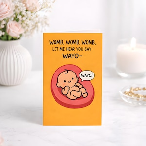 May include: A greeting card with a cartoon baby inside a womb, set against an orange background. The text reads "WOMB, WOMB, WOMB, LET ME HEAR YOU SAY WAYO-". A speech bubble says "WAYO!".