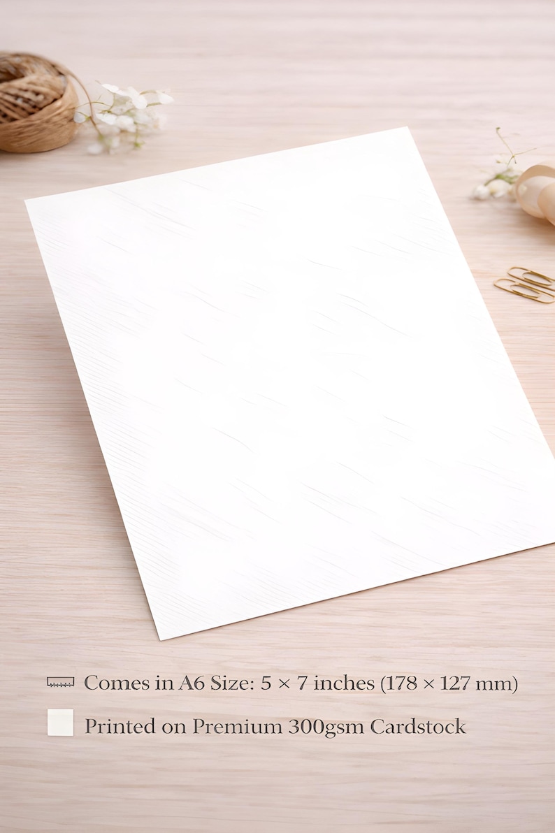 May include: A white A6 card, measuring 5 x 7 inches (178 x 127 mm), with a subtle textured pattern. The card is printed on premium 300gsm cardstock. The image shows the card at an angle, with a wooden surface in the background.