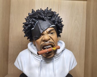 May include: A bust of Method Man featuring a figure with dark curly hair, a black headband, and a white hoodie. The figure has a brown cigar in their mouth with silver rings and is mounted on a black circular base with the text METHOD MAN in yellow.