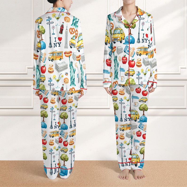 Puede incluir: Conjunto de pijama blanco con un estampado colorido con tem&aacute;tica de la ciudad de Nueva York. La parte superior de manga larga y los pantalones presentan monumentos ic&oacute;nicos, alimentos y el texto "I NY". El ribete rojo acent&uacute;a los bordes del pijama.