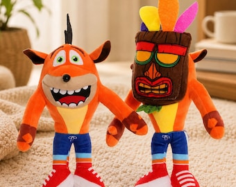 May include: Two plush toys of the video game character Crash Bandicoot. The toys are orange with white, red, and blue accents. One toy has a mask. Both toys are wearing blue shorts and red shoes.