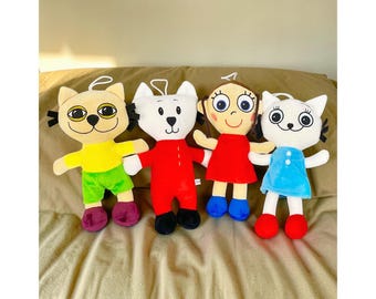 May include: Four plush dolls: a yellow cat, a white bear, a girl, and a white cat. The cat dolls wear yellow and green, the bear wears red, the girl wears red, and the last cat wears blue. Each doll has a white loop for hanging.