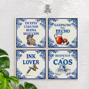 Puede incluir: Cuatro azulejos cuadrados de cerámica con bordes decorativos en azul y blanco. Los azulejos muestran ilustraciones y texto: un tocadiscos con 'EN ESTA CASA HAY BUENA SELECCIÓN', gazpacho con 'GAZPACHO PAL PECHO', una máquina de tatuar con 'INK LOVER' y un desorden con 'RESPETEN MI CAOS'.