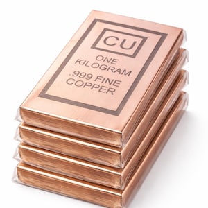 Może przedstawiać: Stos czterech miedzianych sztabek, każda owinięta w przezroczysty plastik. Prostokątne sztabki w kolorze miedzi mają napis "CU", "ONE KILOGRAM" i ".999 FINE COPPER".