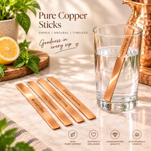 Peut inclure: Quatre bâtonnets rectangulaires en cuivre pur aux bords arrondis. Trois bâtonnets sont posés à plat, gravés avec les phrases Good Vibes, Stay Hydrated, Healthy Living et Better Tomorrow. Un bâtonnet est dans un verre d'eau.