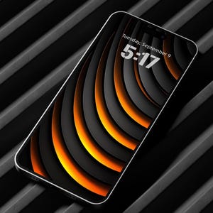 May include: A smartphone with a black and orange abstract design on the screen. The screen displays the time as 5:17 and the date as Tuesday, September 9. The phone has a silver frame and is angled on a black, ridged surface.