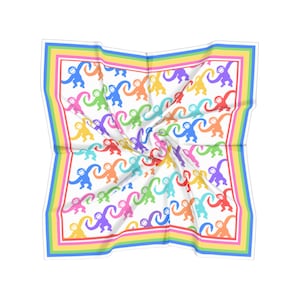 May include: A square white scarf with a repeating pattern of colorful monkeys. The monkeys are in shades of red, orange, yellow, green, blue, and purple. The scarf has a rainbow border with stripes of pink, yellow, green, and blue.
