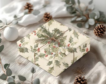 May include: A square gift box wrapped in paper with a holly and berry pattern. The box is tied with twine and adorned with a sprig of greenery. The background includes pine cones, eucalyptus, and a white ornament, creating a festive holiday theme.