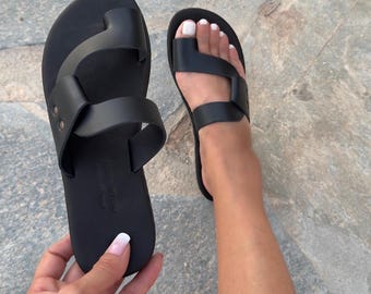 Sandalias negras de piel griega con tira minimalista en el dedo del pie y suela acolchada suave para mujer.