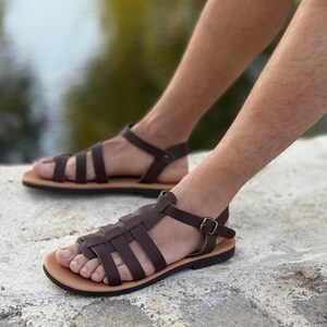 Pu&ograve; includere: Sandali in pelle marrone con un design intrecciato e cinturini alla caviglia. I sandali hanno una suola marrone chiaro e una chiusura con fibbia. Questi sandali sono un'opzione di calzature elegante.