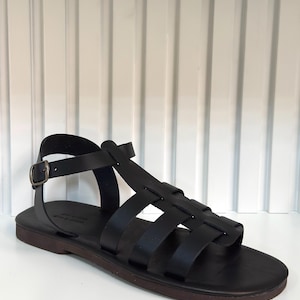Pu&ograve; includere: Sandalo in pelle nera con pi&ugrave; cinturini e chiusura con fibbia. Il sandalo ha una suola marrone scuro e un design semplice e classico. Progettato per il comfort e lo stile.
