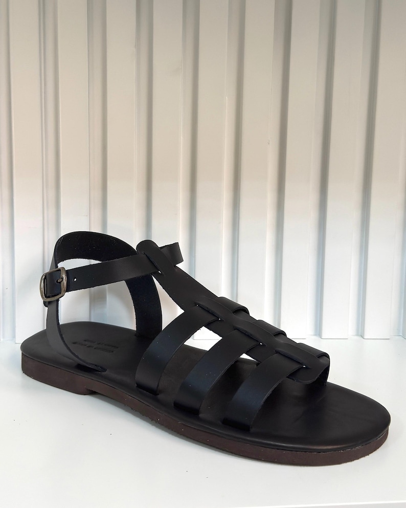 Pu&ograve; includere: Sandalo in pelle nera con pi&ugrave; cinturini e chiusura con fibbia. Il sandalo ha una suola marrone scuro e un design semplice e classico. Progettato per il comfort e lo stile.