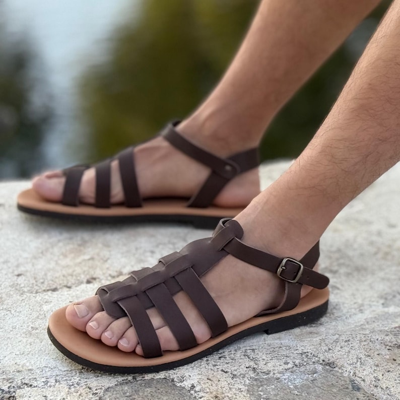 Pu&ograve; includere: Sandali in pelle marrone con un design intrecciato sulla tomaia e chiusura con fibbia. I sandali hanno una suola marrone chiaro e un cinturino alla caviglia marrone scuro. Comodi ed eleganti.