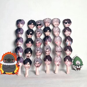 May include: A collection of plush doll heads with various facial expressions and hairstyles. Some dolls wear sunglasses or glasses. A cartoon bird and a tree-shaped doll are also present.