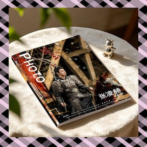 May include: A rectangular photo album featuring a cover image of a person in dark, ornate historical armor holding a spear. The cover includes the white text "PHOTO" and Chinese characters, with a small metallic bear figurine placed on the top right.