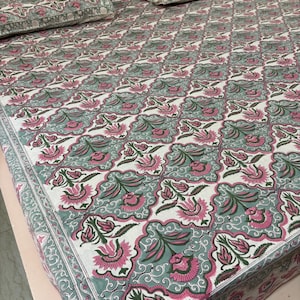 Könnte beinhalten: Bettwäsche-Set mit einem floralen Muster in Rosa, Grün und Weiß. Das Set beinhaltet einen Bettbezug, ein Spannbetttuch und zwei Kissenbezüge. Das Muster ist ein sich wiederholendes Blumenmotiv mit einem dekorativen Rand.
