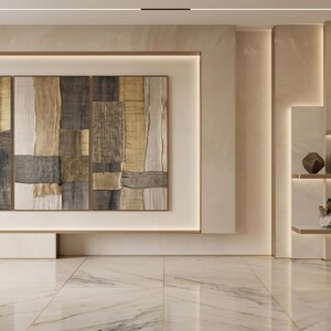 May include: A triptych wall art piece featuring abstract vertical panels in shades of gold, beige, and charcoal gray. The artwork is displayed on a light-colored wall with integrated linear lighting, adjacent to shelves holding decorative vases and crystals.