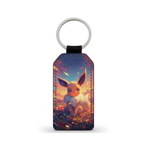 May include: A keychain with a silver ring and a black strap, displaying an Eevee character illustration against a sunset. The rectangular tag features a detailed, colourful artwork. The design evokes a sense of fantasy with its vibrant hues and imagery.