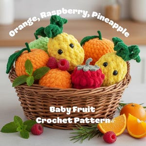 Op de afbeelding: Een gevlochten mand gevuld met gehaakt fruit, waaronder sinaasappels, frambozen en ananassen. De vruchten zijn in heldere kleuren met groene bladeren en stelen. De tekst "Orange, Raspberry, Pineapple" en "Baby Fruit Crochet Pattern" worden weergegeven.