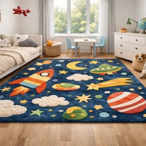 以下が含まれることがあります： 宇宙をテーマにした紺色の子供用ラグ。カラフルなロケット、惑星、星、雲、三日月、UFOが特徴です。ベッド、テーブル、ティピーのある子供部屋に敷かれています。