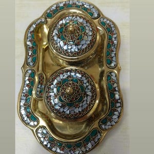 Könnte beinhalten: Ein dekoratives Servierset aus Messing mit einem Tablett, zwei Behältern mit Deckel und einem Löffel. Das Set ist mit einem Mosaikmuster aus weißen, grünen und roten Steinen verziert. Das Tablett ist ca. 25 cm lang.
