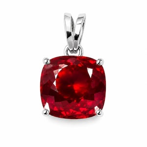 May include: A cushion-cut vibrant red gemstone pendant set in a polished silver-toned metal frame. The square-shaped stone features multifaceted surfaces that reflect light, held by four small prongs and topped with a silver-toned metal bail.