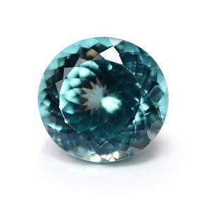 Könnte beinhalten: Ein runder, facettierter Edelstein in Teal-Farbe. Der Edelstein hat einen Brillantschliff, der das Licht reflektiert und einen funkelnden Effekt erzeugt. Der Edelstein ist vor einem weißen Hintergrund platziert, um seine Farbe und Klarheit hervorzuheben.