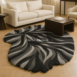 May include: A modern, abstract rug in shades of gray and black, featuring a flowing, organic design. The rug's pattern resembles layered waves or petals, creating a textured, three-dimensional effect. The text "Marten Rug Decor" is visible on the rug.