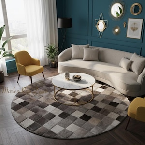 Könnte beinhalten: Ein modernes Wohnzimmer mit einem geschwungenen beigen Sofa, zwei gelben Sesseln und einem runden Couchtisch mit Marmorplatte. Ein gemusterter Teppich in Grau- und Brauntönen liegt auf dem Boden. Dekorative Spiegel schmücken die türkisfarbene Wand.