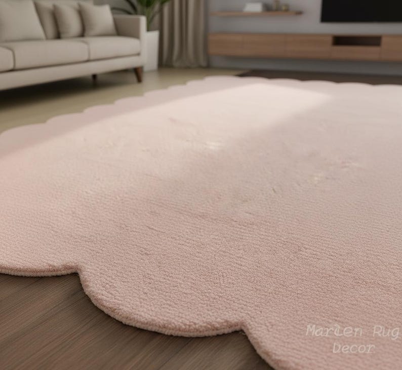 Puede incluir: Una alfombra grande de color rosa claro con un borde festoneado. La alfombra tiene una superficie suave y texturizada y est&aacute; colocada sobre un suelo de madera. Las palabras "Marten Rug Decor" est&aacute;n impresas en la esquina inferior derecha.