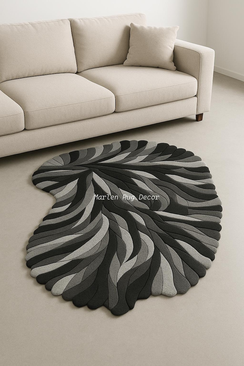 May include: A gray and black area rug with a unique, organic shape. The rug features a layered design of curved lines in varying shades of gray and black. The text "Marlen Rug Decor" is visible on the rug.