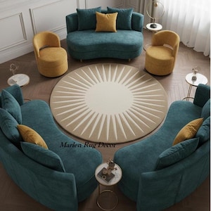 Pode incluir: Um arranjo de sala de estar com sofás azuis-turquesa e cadeiras amarelo-mostarda em torno de um tapete redondo com um design de raios de sol. O tapete é bege com raios creme. Mesas laterais pequenas e almofadas completam o ambiente. O texto "Marlen Rug Decor" é visível.