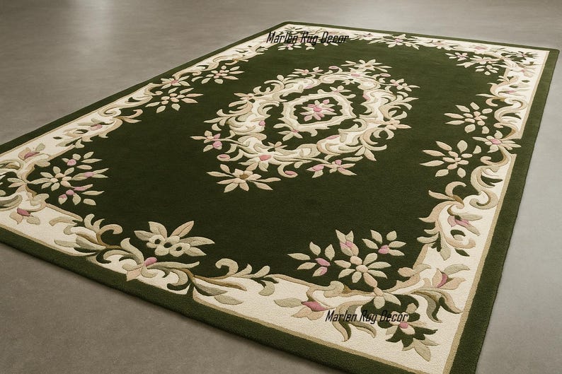 May include: A rectangular green rug with an ornate floral design. The rug features a cream-colored border with floral and scrollwork patterns. The central design is a cream-colored medallion with pink accents. The rug is a decorative floor covering.