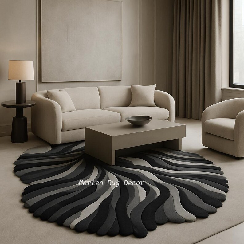 May include: A living room scene featuring a beige sofa, a coffee table, and a round rug with a wave-like pattern in shades of gray and black. A side table with a lamp and a matching armchair complete the decor. The rug has the text "Marlen Rug Decor".