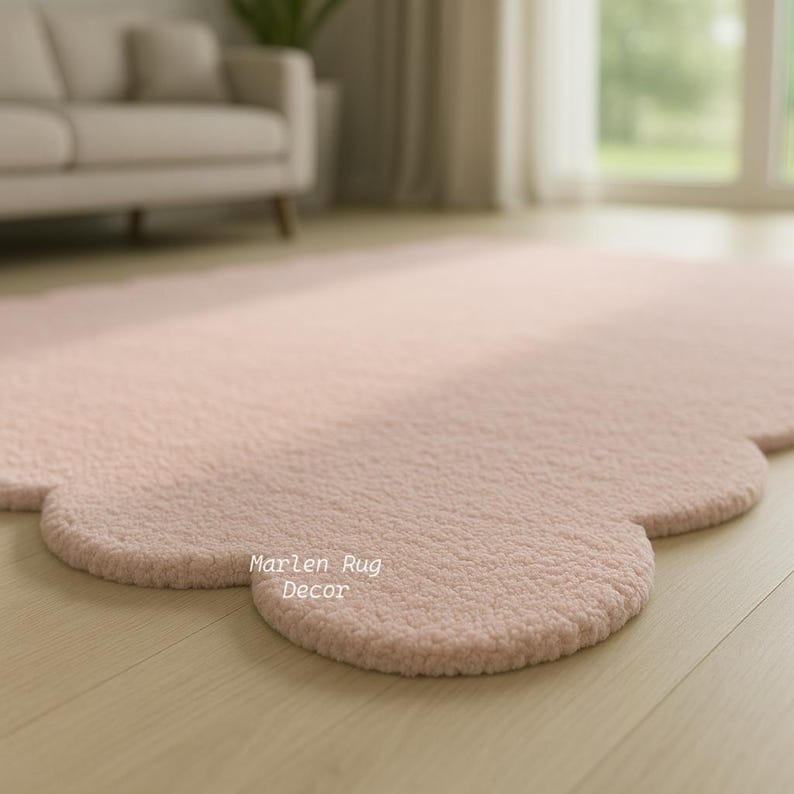 Puede incluir: Una alfombra rosa claro en forma de nube con una superficie texturizada. La alfombra est&aacute; sobre un suelo de madera clara. Las palabras "Marlen Rug Decor" est&aacute;n impresas en la alfombra.