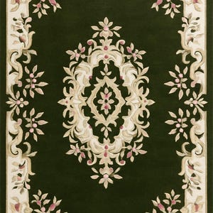 May include: A rectangular dark green rug with an ornate floral design. The rug features a central medallion and a border of stylized flowers in cream, beige, and pink. The rug's design is symmetrical and detailed, with a classic aesthetic.