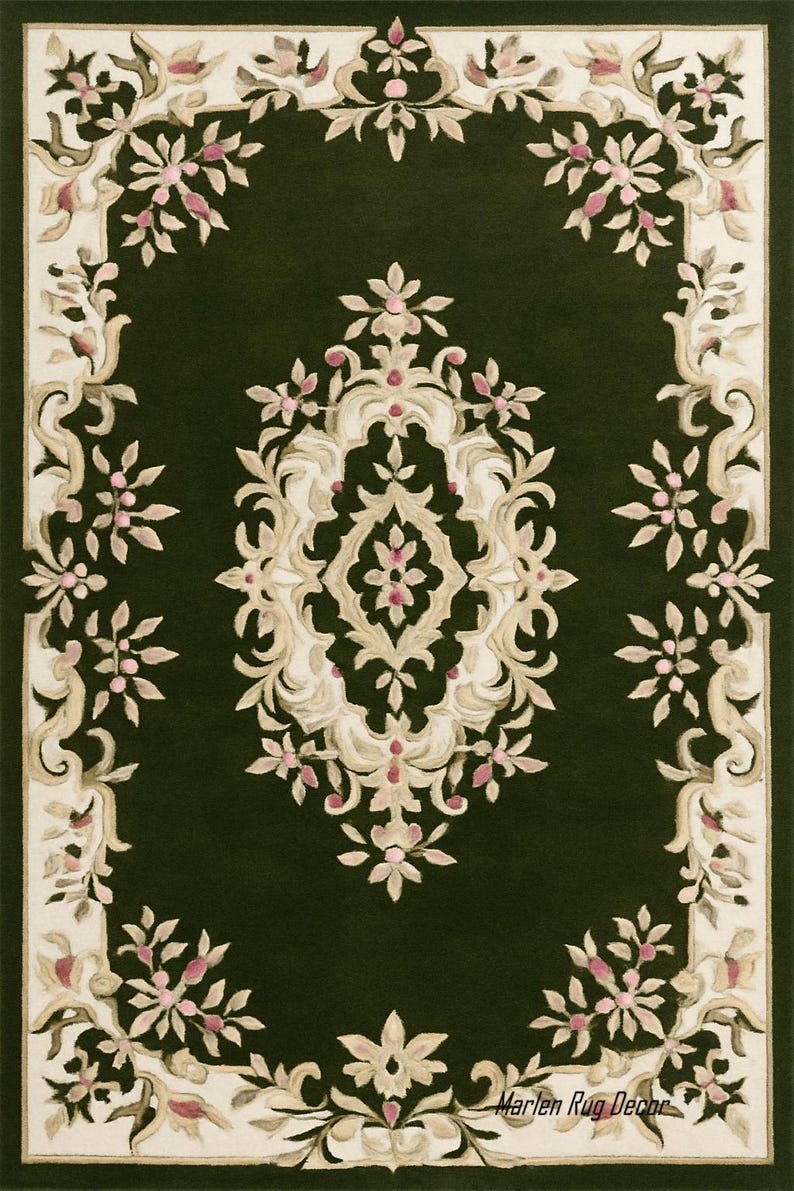 May include: A rectangular dark green rug with an ornate floral design. The rug features a central medallion and a border of stylized flowers in cream, beige, and pink. The rug's design is symmetrical and detailed, with a classic aesthetic.
