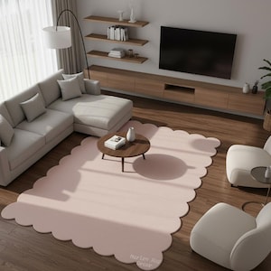 Puede incluir: Un sal&oacute;n moderno con un sof&aacute; esquinero gris claro, dos sillones color crema y una mesa de centro redonda. Una gran alfombra rosa rubor con bordes festoneados ancla el espacio. Un televisor de pantalla plana est&aacute; montado en una consola de madera.