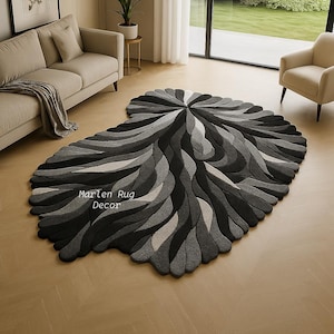 May include: A large, abstract rug with a leaf-like design in shades of gray and black. The rug features a swirling pattern and the text "Marlen Rug Decor". It is placed on a light-colored wooden floor, complementing the neutral tones of the room.
