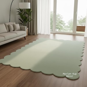 Puede incluir: Una alfombra grande, verde salvia, con un borde festoneado sobre un suelo de madera. La alfombra rectangular tiene esquinas redondeadas y una superficie texturizada. Las palabras "Marlen Rug Decor" est&aacute;n impresas en la alfombra.