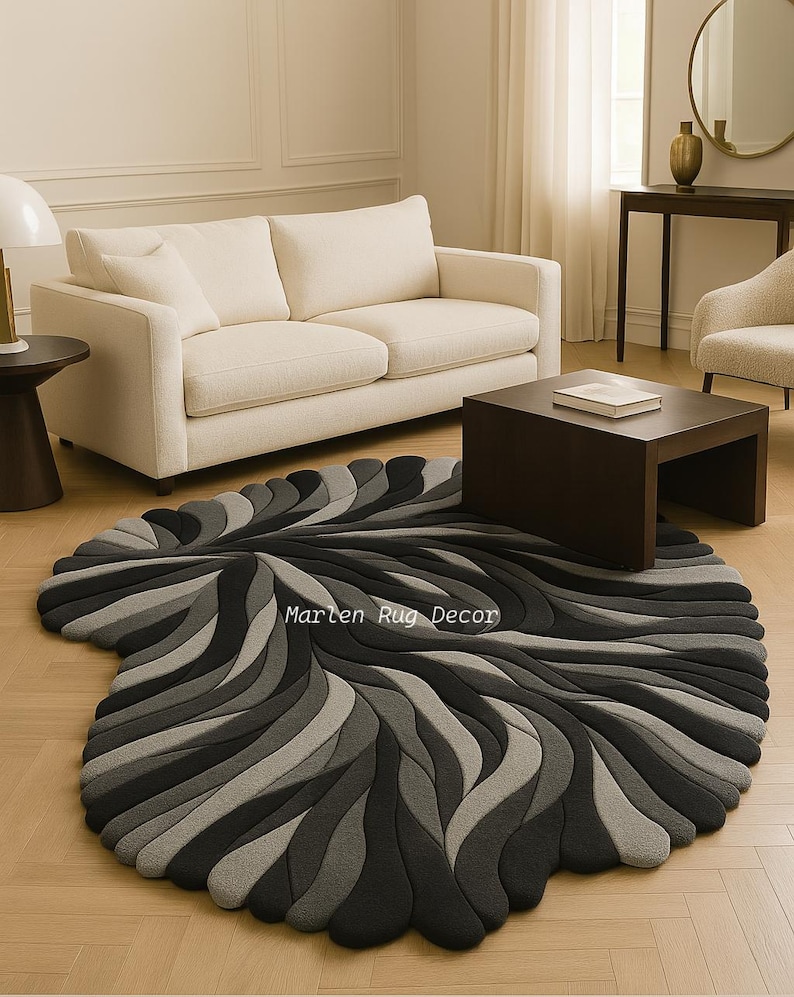 May include: A modern, abstract rug in shades of gray and black, featuring a flowing, organic design. The rug's pattern resembles layered waves or petals, creating a textured, three-dimensional effect. The text "Marten Rug Decor" is visible on the rug.
