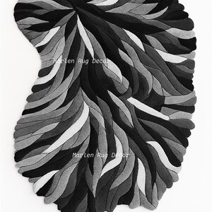 May include: A grayscale rug with a unique, organic shape. The rug features a pattern of layered, curved lines in shades of black, gray, and white. The text "Marlen Rug Decor" is visible on the rug.