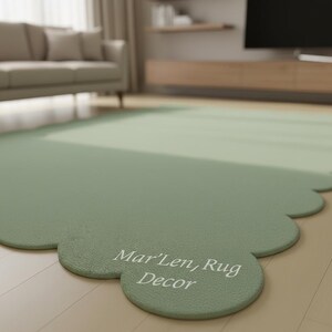 Puede incluir: Una alfombra verde salvia con borde festoneado. La alfombra tiene el texto "Mar'Len, Rug Decor" impreso. La alfombra est&aacute; sobre un suelo de madera clara. Un sof&aacute; y un televisor est&aacute;n en el fondo.