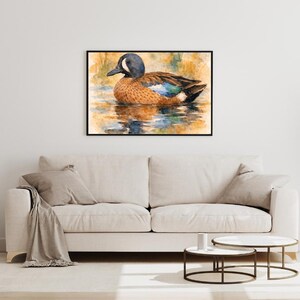May include: A framed watercolor painting of a duck floating on water. The duck has a blue head, brown body, and blue and brown wings. The water reflects the duck and the surrounding colors of orange and green.