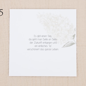 May include: A square white card featuring a faint, light gray illustration of a flower cluster in the upper right corner. The card displays the German text: Es gibt einen Tag, da geht man Seite an Seite der Zukunft entgegen und ein einfaches Ja versch&ouml;nert das ganze Leben.