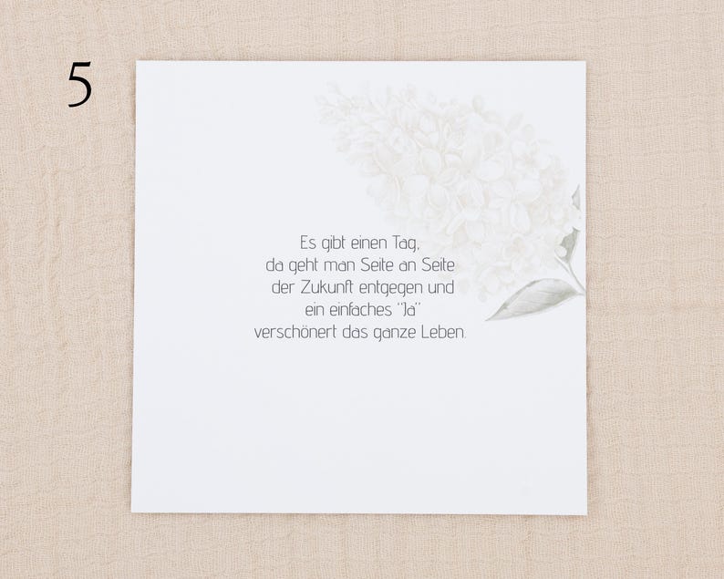 May include: A square white card featuring a faint, light gray illustration of a flower cluster in the upper right corner. The card displays the German text: Es gibt einen Tag, da geht man Seite an Seite der Zukunft entgegen und ein einfaches Ja versch&ouml;nert das ganze Leben.