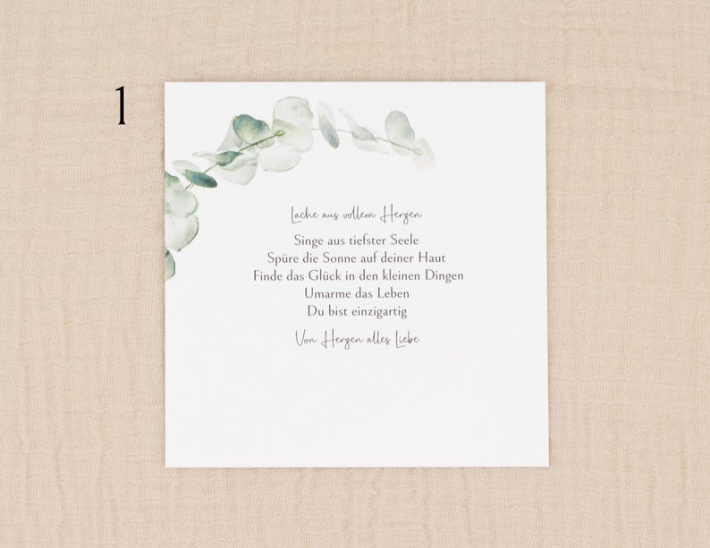 May include: A white card with a watercolor eucalyptus design in the upper left corner. The card features handwritten text in German, including phrases like "Lache aus vollem Herzen" and "Du bist einzigartig."