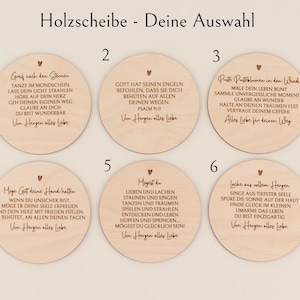 May include: A collection of six wooden discs with German text and heart illustrations. Each disc features a unique message, with phrases like "Gott hat seinen Engeln" and "Greif nach den Sternen" inscribed in a decorative font. The discs are light brown.