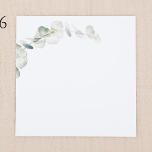 May include: A square white card featuring the number 6 in the top left corner and a delicate watercolor illustration of a curved eucalyptus branch with soft green and grey leaves extending from the left side across the top edge.